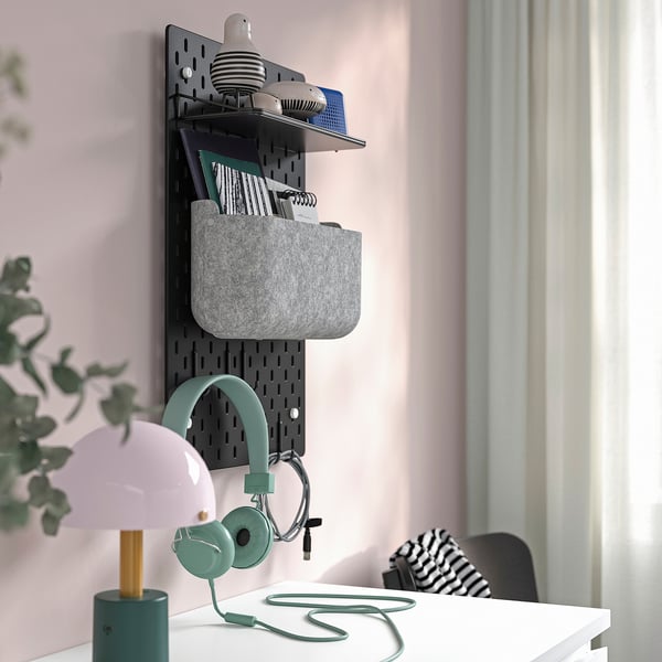 Organisierte Wandklammertafel mit Regalen für Büromaterial, Kopfhörer und Lampen, die Ordnung und Zugänglichkeit fördern.