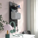 Organisierte Wandklammertafel mit Regalen für Büromaterial, Kopfhörer und Lampen, die Ordnung und Zugänglichkeit fördern.