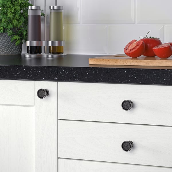 Moderne Küchentheke mit weißen Schränken und SKRUVSHULT-Knöpfen; Knapper und Tomaten ausgestellt.