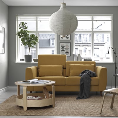 Modernes Wohnzimmer mit gelbem Sofa, Kissen, Holztisch, Dekor und großem Fenster.