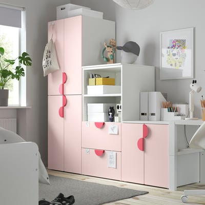 Zeigt einen hellrosa SMÅSTAD-Kleiderschrank, rechteckig und modular, ideal für Kinderzimmer, mit mehreren Fächern zur Aufbewahrung von Kleidung.