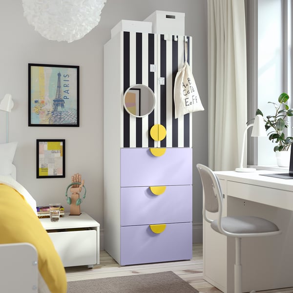Modernes Schlafzimmer mit gestreiftem Kleiderschrank, lila Schubladen, rundem Spiegel, Schreibtisch, Kunst und Nachttisch mit Kopfhörern und Büchern.