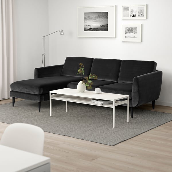 Modernes Wohnzimmer mit dunkelgrauem Sofa, weißem Couchtisch und minimalistischem Dekor.