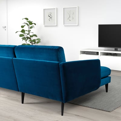 Modernes Wohnzimmer mit blauem Samtsofa SMEDSTORP, minimalistischem Dekor, grüner Pflanze.