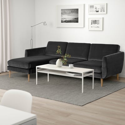 Minimalistischer Wohnbereich: dunkelgraues SMEDSTORP 3-Sitzer-Sofa, moderner Couchtisch, heller Holzboden, schwarz-weiße Wandkunst, geschwungene Lampe.