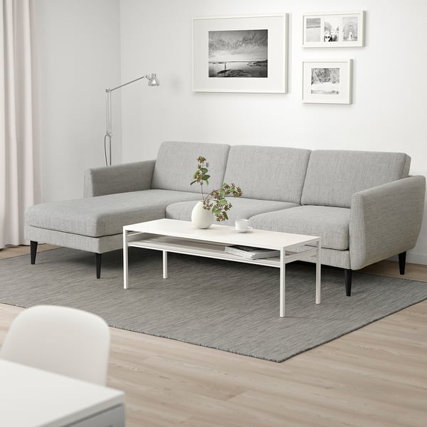 Modernes graues Sofa im Mid-Century-Stil, minimalistisches Wohnzimmer mit Kunst, Couchtisch, Lampe und Teppich.