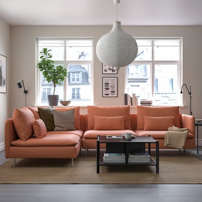 Modernes Wohnzimmer mit orangefarbenem SÖDERHAMN-Sofa, Plüschkissen, Couchtisch, Pendelleuchte und Fensterbegrünung.