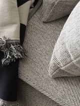 Schwarze und beige Decken mit Fransen, die in der Nahaufnahme ordentlich gefaltet sind.