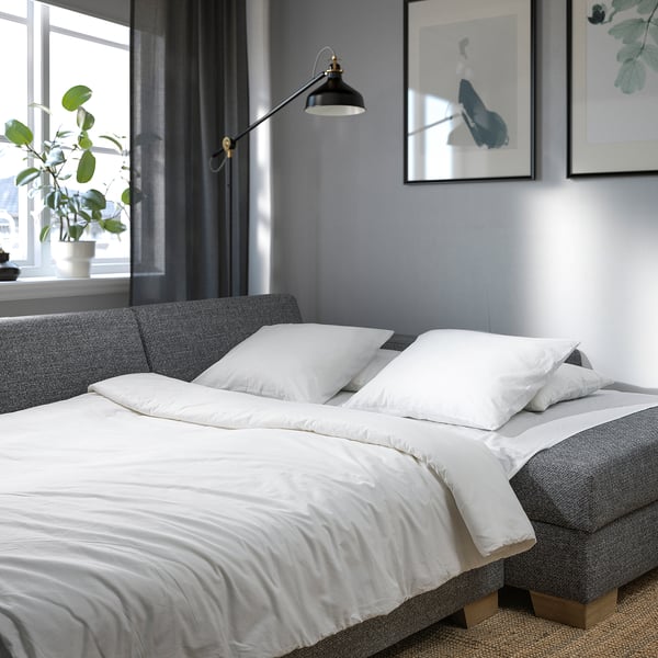 Verwandelndes Schlafsofa mit klaren Linien und weißen Kissen, ideal für moderne Innenräume.