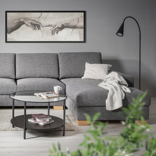 Ein modernes graues Sektionssofa mit einem Couchtisch und einem Wandgemälde in einem minimalistischen Wohnzimmer.
