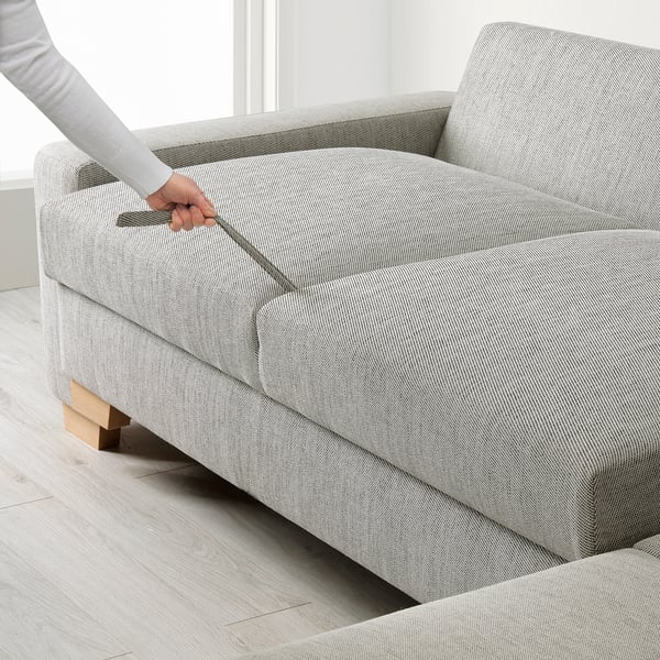 Person stellt den Mechanismus des Schlafsofas ein und demonstriert die umwandelbare Funktionalität.