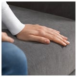 Die Hand einer Person ruht auf einem grauen SÖRVALLEN-Sofa und zeigt sein modernes, minimalistisches Design.