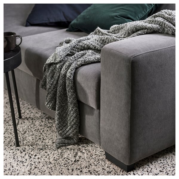 Gemütliches modernes graues Sofa mit Strickdecke und Kissen, schwarzer Beistelltisch mit Tasse.