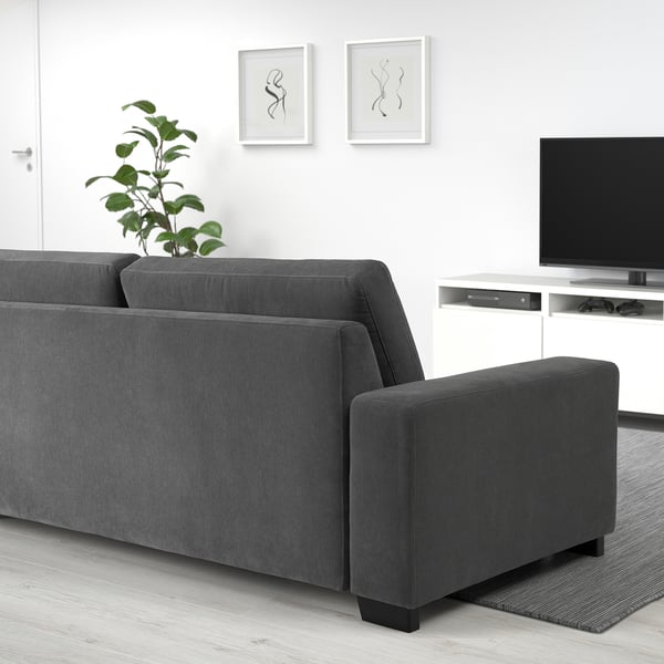 Graues SÖRVALLEN Sofa in minimalistischem Wohnzimmer mit Teppich, Pflanze, Kunst und TV.