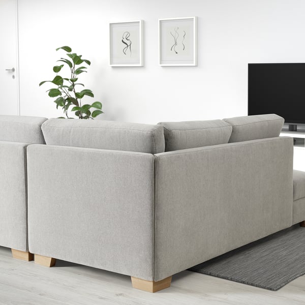 Hellgraues SÖRVALLEN-Sofa, modernes minimalistisches Design, groß, mit Kissen, in der Nähe von Pflanzen und Fernseher, in einem minimalistischen Raum.