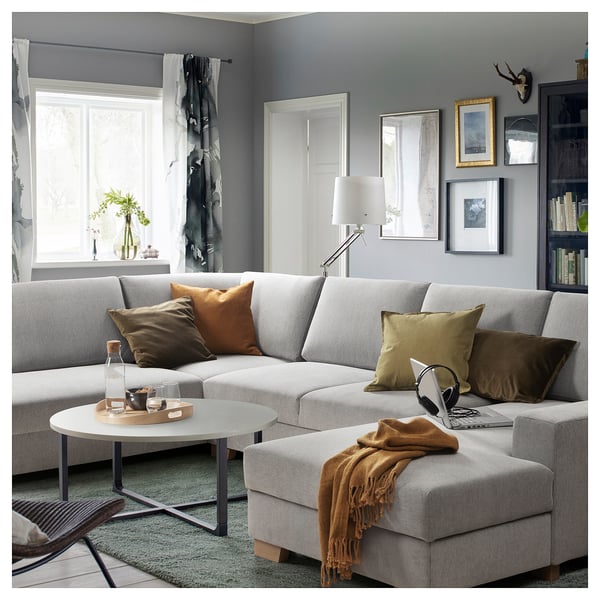 Modernes graues L-förmiges Sofa mit bunten Kissen, Couchtisch und gemütlicher Einrichtung in stilvollem Wohnzimmer mit großen Fenstern.