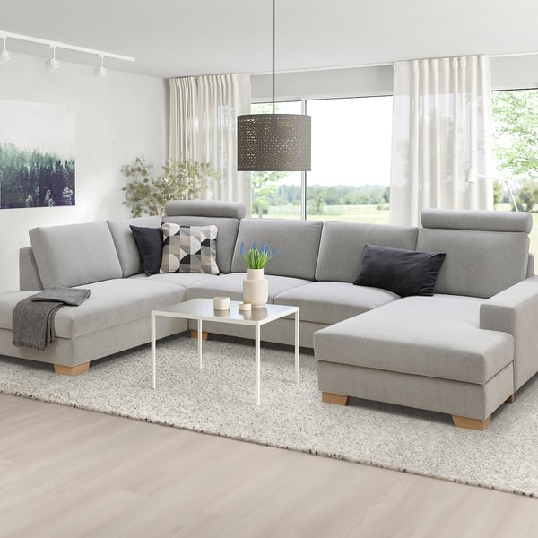 Modernes graues U-förmiges Sofa im minimalistischen Stil, groß, mit Kissen, Tisch, Teppich und Vorhängen.