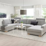 Modernes graues U-förmiges Sofa im minimalistischen Stil, groß, mit Kissen, Tisch, Teppich und Vorhängen.
