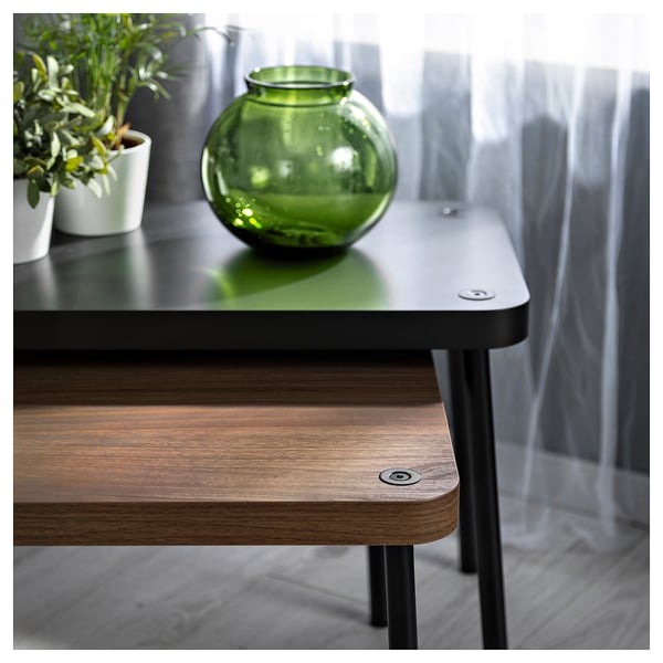 Minimalistische, platzsparende Tische aus dunklem Holz und schwarzem Metall mit einer grünen Vase und einer Pflanze auf der Platte.