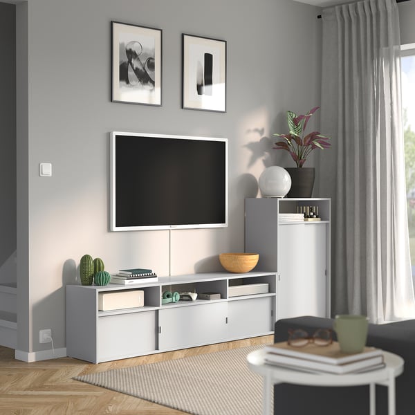 Modernes Wohnzimmer mit SPIKSMED TV-Ständer und Schrank. Die weißen Unterkünfte verfügen über einen TV und ein Dekor. Graue Wände, Holzböden, dunkle Möbel.