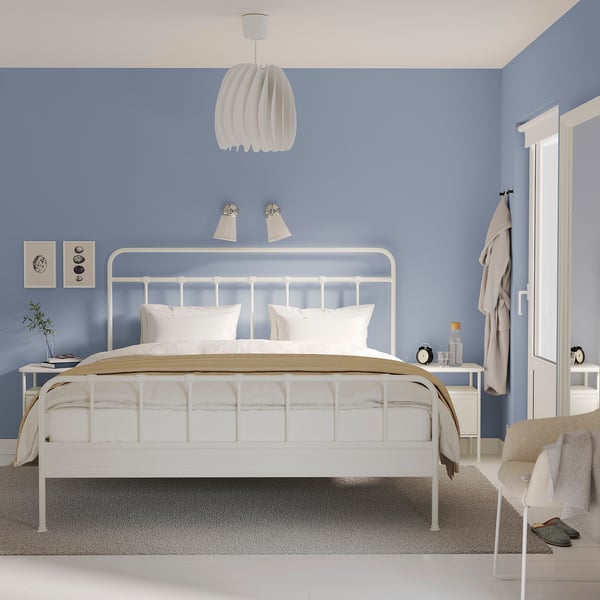 Minimalistisches Schlafzimmer mit STJÄRNÖ-Bett, blauen Wänden, Pendelleuchte, Gråfjället-Nachttisch, Teppich und Wandlampen.