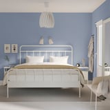 Minimalistisches Schlafzimmer mit STJÄRNÖ-Bett, blauen Wänden, Pendelleuchte, Gråfjället-Nachttisch, Teppich und Wandlampen.