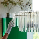 Stellt den modernen Kronleuchter mit Glasrohren und Messinghaken von Hand ein und fixiert die Lichtposition.