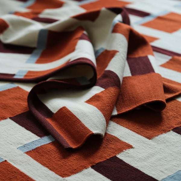 Geometrischer Wollteppich mit komplizierten handgewebten Mustern in Orange-, Rot- und Weißtönen. Hochwertige Textur, perfekt für gemütliche Innenräume.