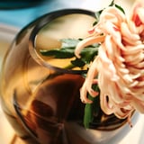 Schöne Glasvase, elegant geformt, mit blühenden Blumen. Ästhetisch und dekorativ, mit einer reichhaltigen, glatten Textur.