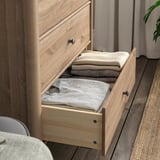 Eine offene Kommode aus Holz mit ordentlich gefalteten Kleidungsstücken, die ihre Aufbewahrung und Organisation zeigen.