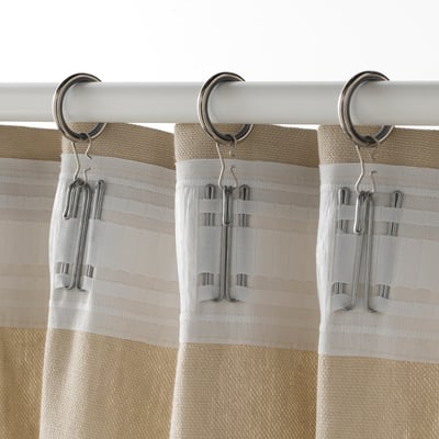 Beige Vorhänge hängen an silbernen Haken an weißem Stab.