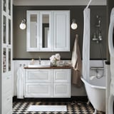 Schwarz-weißes Badezimmer mit TÄNNFORSEN-Waschtisch, Klauenfußwanne und kariertem Boden.