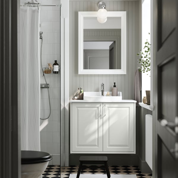 Ein weißer TÄNNFORSEN Badezimmerschrank, schmal, mit Waschbecken, Spiegel und schwarz-weißem Boden.