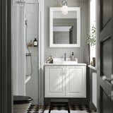 Ein weißer TÄNNFORSEN Badezimmerschrank, schmal, mit Waschbecken, Spiegel und schwarz-weißem Boden.