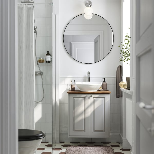 Modernes Badezimmer mit grauem TÄNNFORSEN-Waschtisch, weißem Waschbecken, Spiegel und Glasduschtür.