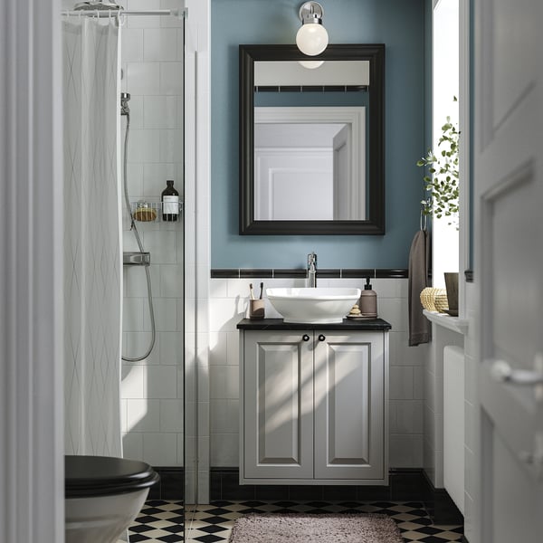 Modernes Badezimmer mit TÄNNFORSEN-Waschtisch, schwarzer Theke, Waschbecken, Spiegel und Glasdusche.