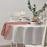 TAGGSIMPA rot gestreifte Tischdecke auf rundem Tisch, zwei weiße Stühle, vier Glasteller, Schalen, Weingläser, Grünzeug, Wasserkrug, recyceltes Polyester.