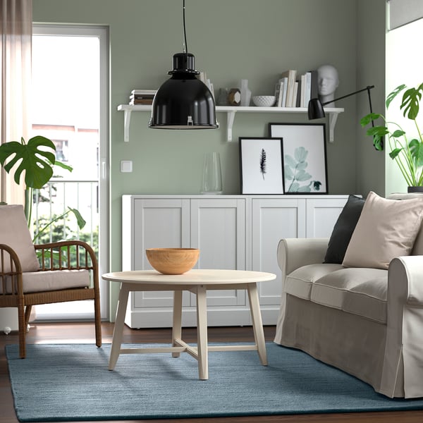 Modernes Wohnzimmer mit graublauem Teppich, Couchtisch, Stühlen und Pendelleuchte.