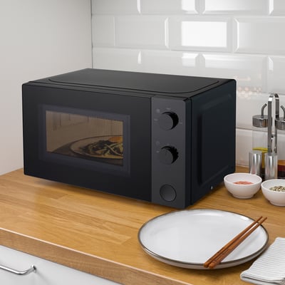 Schwarze TILLREDA Mikrowelle auf Holztheke mit Teller und Essstäbchen.