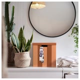 Moderne Ecke: TJENA orangefarbene Box mit Fotos, Pflanzen, Spiegel, weiße Arbeitsplatte.