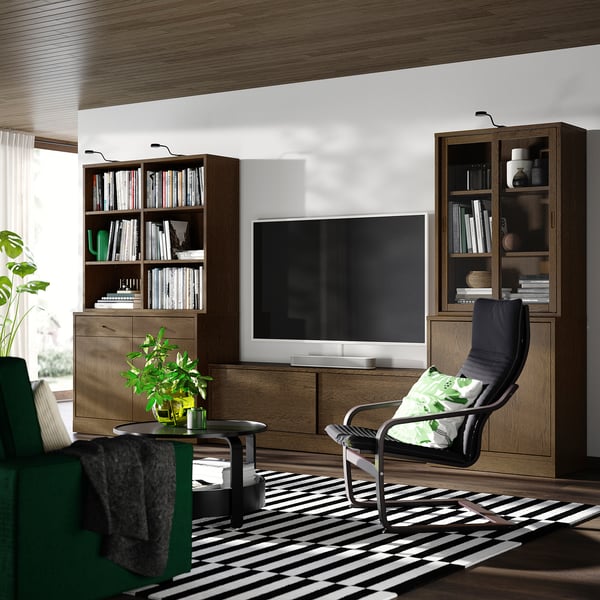Modernes Wohnzimmer mit großem Fernseher, dunklem Stuhl, Holzregalen voller Bücher und einem gestreiften Teppich.