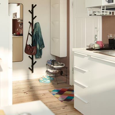 Bunte geometrische TORGPLATS Fußmatte in der Nähe von Schuhregal und Kleiderhaken.