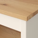 Nahaufnahme eines Möbels mit Holzplatte mit glatter, gleichmäßiger Maserung und Fehlern, getragen von sauberen weißen Beinen.