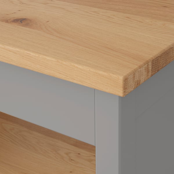 Nahaufnahme einer hochwertigen Holztischplatte mit glatter, natürlicher Maserung und veredelten Kanten, getragen von stabilen grauen Metallbeinen.