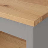 Nahaufnahme einer hochwertigen Holztischplatte mit glatter, natürlicher Maserung und veredelten Kanten, getragen von stabilen grauen Metallbeinen.