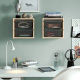 TROFAST Regale mit dunklen Boxen bieten Platz für Sportartikel und Bücher. Der Schreibtisch darunter hat eine Lampe, Bücher, Stifte, Tablet, Wasserflasche an einer hellblauen Wand.
