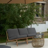 Graues TVARÖ-Sofa an Deck mit Tisch und Laub.