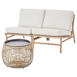 Handgeflochtenes Outdoor-Sofa aus natürlichem Rattan mit beigen Kissen und passendem Tisch. Modernes, modulares und witterungsbeständiges Design.