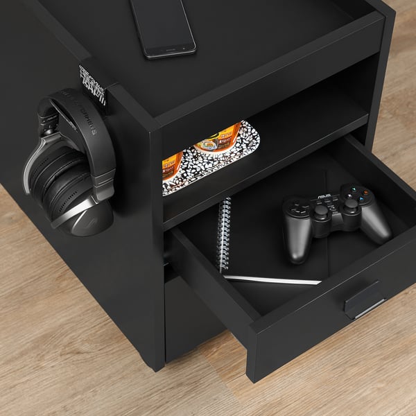 Schwarze Gaming-Schublade mit offener Schublade mit Notebook, Stift und Gaming-Controllern. Kopfhörer hängen am seitlichen Haken.