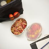 Lunchbehälter mit Obst, Getreide, Orangen und Notizbuch. Perfekt für Mahlzeiten unterwegs.